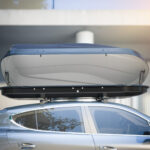 Auto so strešným boxom tesne pred vjazdom do nízkej garáže, ilustrujúce riziko nárazu.