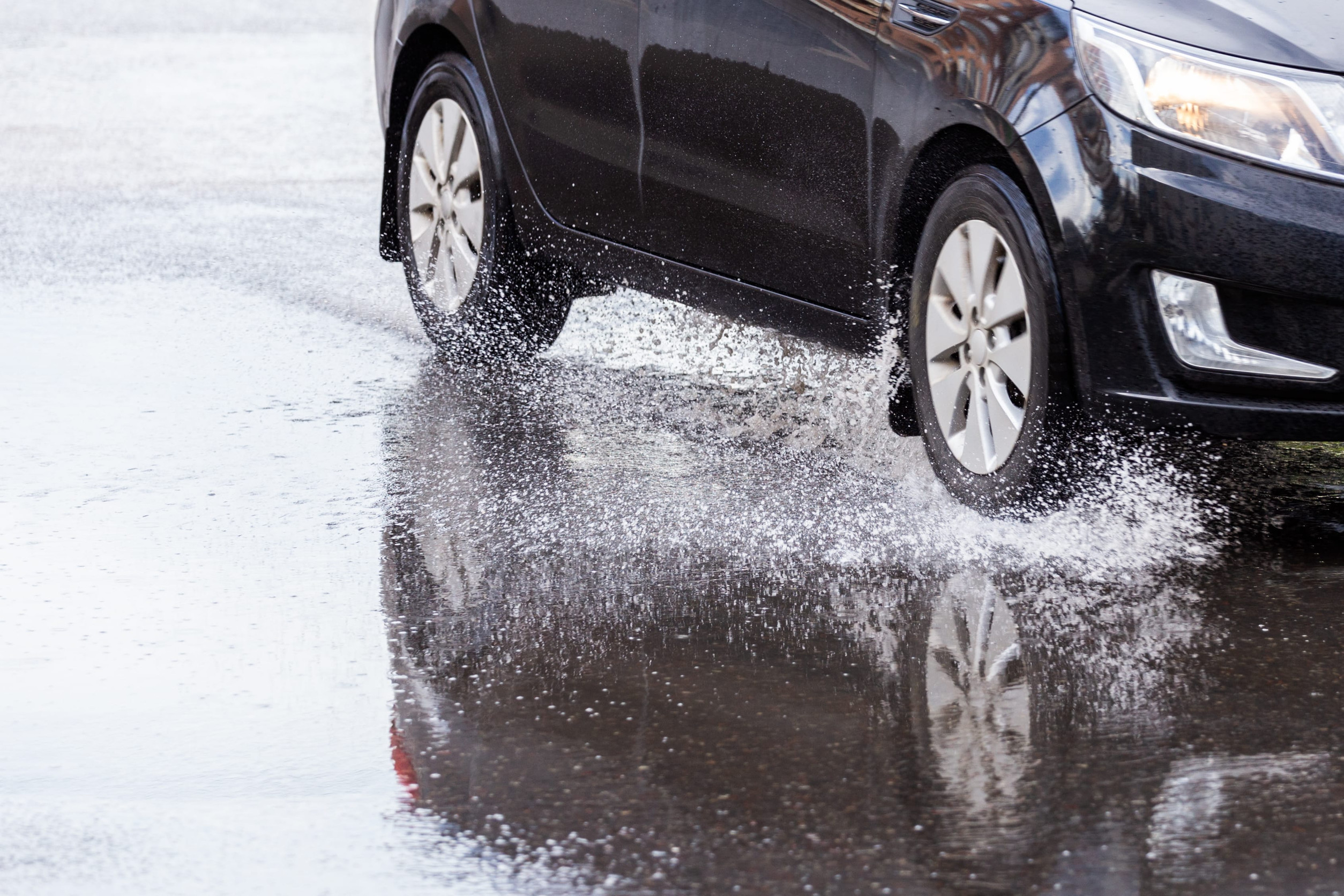 Automobil jazdiaci po mokrej ceste počas silného dažďa s rizikom aquaplaningu.